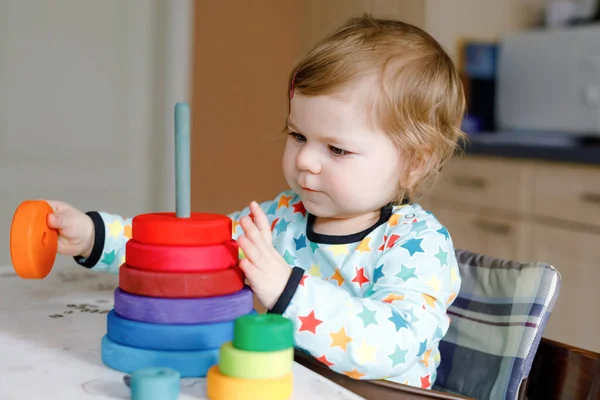 Cute beautiful little baby girl playing with educational toys at home or nursery, indoors. Happy healthy child having fun with colorful wooden rainbow toy pyramid. Kid learning different skills. — Stock Photo, Image