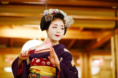 KYOTO, JAPONYA - 18 Mayıs 2015: Japon geleneksel dansını gösteren Maiko çırağı. Maiko bir çırak geyşa. Maikos ozashiki 'deki ziyaretçiler için şarkı söylüyor, shamisen çalıyor veya enstrümanlar çalıyor.