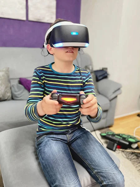 School kid boy experiencing virtual reality video game. Surprised little boy looking in VR glasses. Digital activity for children, cyberspace and modern entertainment.