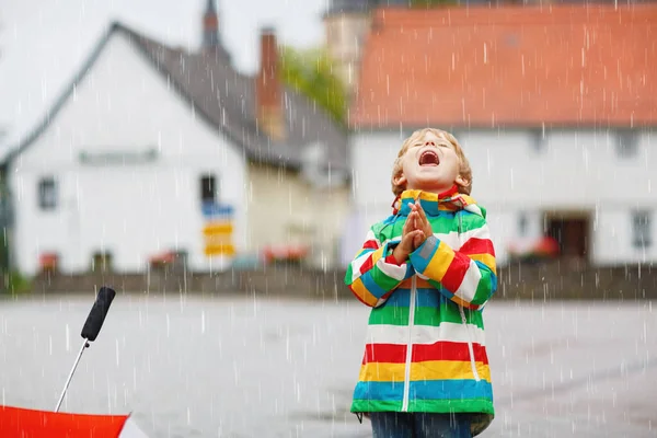 Un bambino che gioca nei giorni di pioggia. Felice bambino positivo divertirsi con la cattura di gocce di pioggia. Ragazzo con i vestiti da pioggia. Bambini e famiglia attività all'aperto nella giornata del maltempo. — Foto Stock