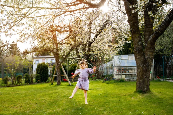 Bonne petite fille tout-petit s'amuser à jouer dans le jardin domestique. Sourire positif enfant en bonne santé courir et sauter sur la cour arrière. Petite fille d'âge préscolaire riant et pleurant. Loisirs actifs et activités en plein air — Photo