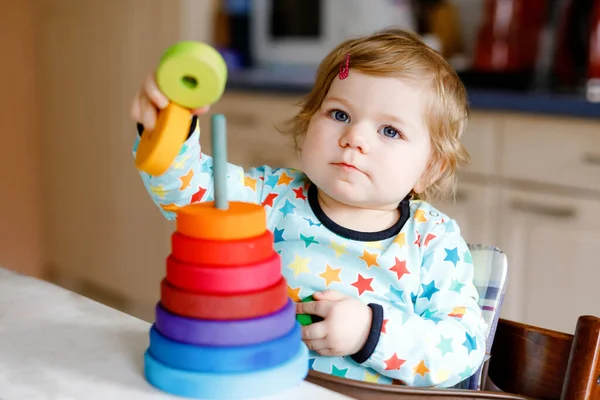 Niedliche schöne kleine Mädchen spielen mit Lernspielzeug zu Hause oder im Kinderzimmer, drinnen. Glückliches gesundes Kind, das Spaß an der bunten hölzernen Regenbogen-Spielzeugpyramide hat. Kind lernt andere Fähigkeiten. — Stockfoto