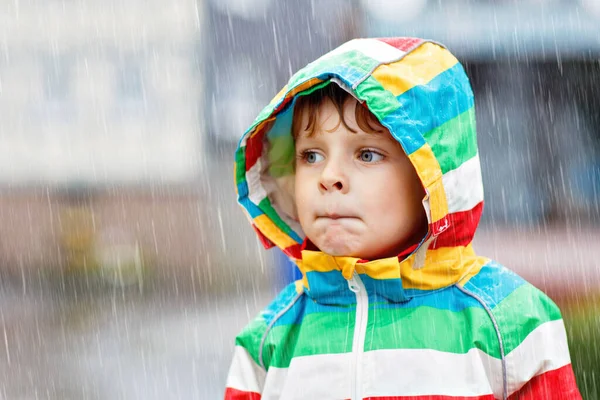 Portrait of little toddler boy playing on rainy day. Happy positive child having fun with catching rain drops. Kid with rain clothes. Children and family outdoor activity on bad weather day. — Stock Photo, Image