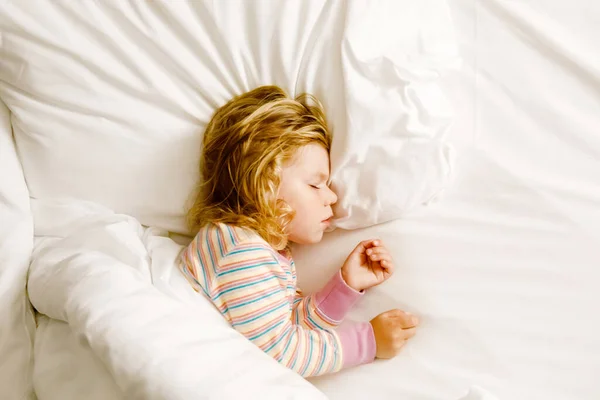 Cute little toddler girl sleeping in big bed of parents. Adorable baby child dreaming in hotel bed on family vacations or at home. — Stock Photo, Image