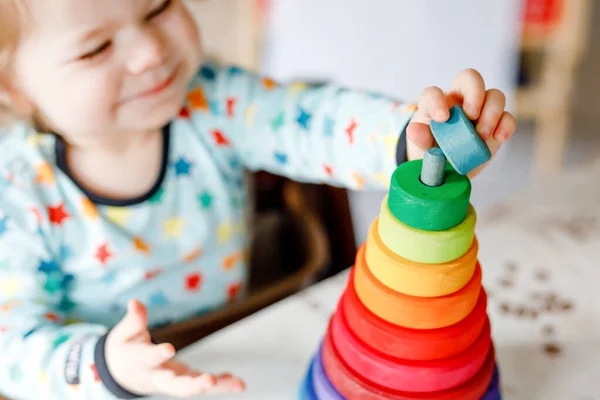 Roztomilá krásná holčička hrající si doma nebo v dětském pokoji se vzdělávacími hračkami. Šťastné zdravé dítě baví s barevné dřevěné duhové hračky pyramidy. Děti se učí různé dovednosti. — Stock fotografie