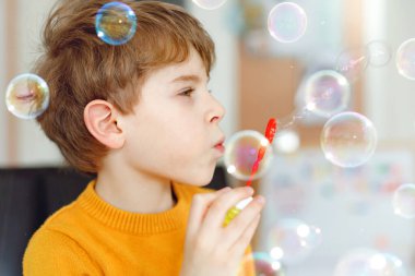 Evde sabun köpüğüyle oynayan mutlu küçük okul çocuğu. Çocuk eğleniyor. Okulda oynayan çocuk, deney yapıyor.