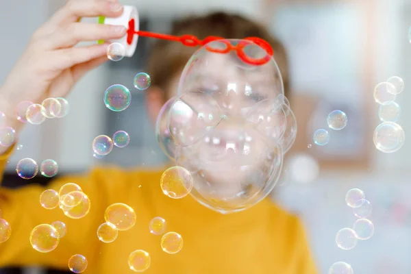 Menino da escola feliz brincando com bolhas de sabão em casa. O miúdo está a divertir-se. Criança brincando na escola, fazendo experiência — Fotografia de Stock