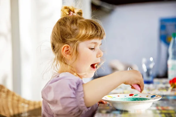 Portrait of happy smiling toddler girl eating pasta on domestic terrace outdoors. Little child with blond hairs enjoy healthy fresh prepared lunch. Happy healthy child and food for children. Royalty Free Stock Photos