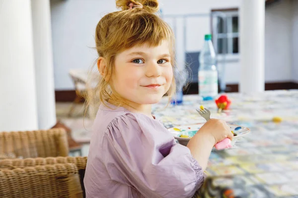 Портрет щасливої усміхненої дівчинки, яка їсть макарони на домашній терасі на відкритому повітрі. Маленька дитина з світлим волоссям насолоджується здоровим свіжим приготованим обідом. Щаслива здорова дитина і їжа для дітей . — стокове фото