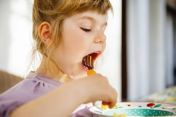 Portret uśmiechniętej dziewczynki jedzącej makaron na tarasie. Małe dziecko z blond włosami delektuje się zdrowym, świeżym lunchem. Szczęśliwe zdrowe dziecko i żywność dla dzieci. — Zdjęcie stockowe