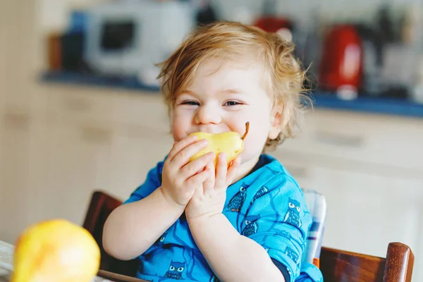 Linda adorable niña comiendo pera fresca. Bebé feliz hambriento de un año sosteniendo fruta. —  Fotos de Stock