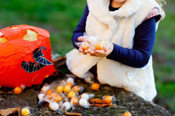 Detailní záběr batolete holka trik nebo dárek na Halloween. Šťastné dítě venku počítá sladkosti z dýňové tašky pro sladké strašení. Rodinná slavnostní sezóna v říjnu. Venkovní aktivita. Trick or treat fun. — Stock fotografie