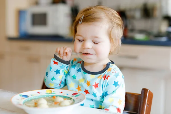 スプーン野菜の麺スープから食べる愛らしい赤ちゃんの女の子。食料、子供、給餌と開発の概念です。かわいい幼児、スプーンが高い椅子に座って自分で食べることを学ぶ娘. — ストック写真