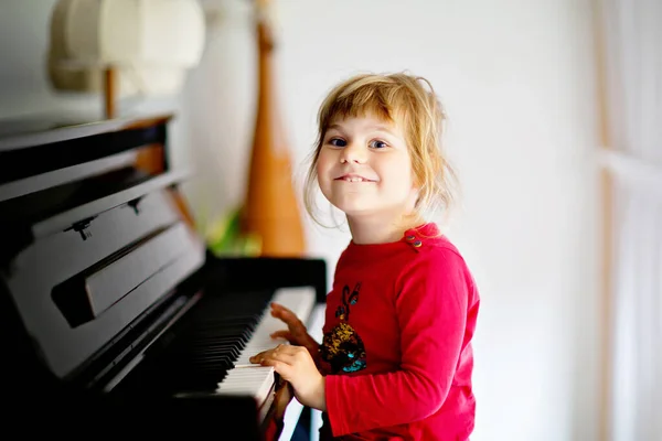 Wunderschönes kleines Mädchen, das im Wohnzimmer Klavier spielt. Nettes Vorschulkind, das Spaß daran hat, ein Musikinstrument zu lernen. Musikalische Früherziehung für Kinder. — Stockfoto