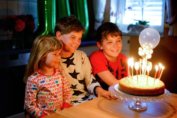 Menino adorável comemorando o décimo aniversário. menina pequena criança, criança irmã e dois filhos meninos irmãos soprando juntos velas no bolo. Retrato familiar saudável feliz com três filhos irmãos — Fotografia de Stock