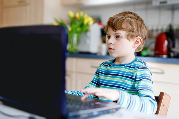 Menino aprendendo em casa no laptop para a escola. Criança do ensino fundamental fazendo lição de casa e usando notebook e gadgets modernos. Conceito de ensino em casa. Ter uma aula de vídeo com o professor. — Fotografia de Stock