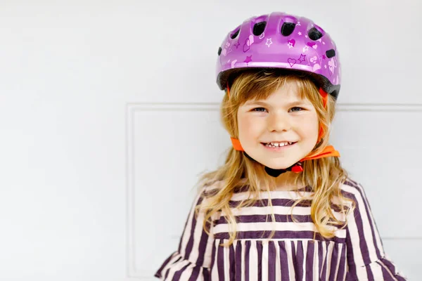 Portrait of happy smiling preschool girl with bycicle helmet on head. Cute toddler child. Safe bike driving with children concept. Safety helmet for kids