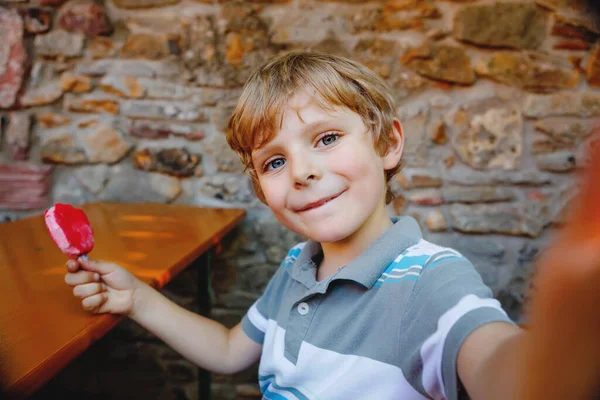 Kid boy tomando selfie com celular durante comer sorvete no dia de verão. criança loira feliz se divertindo. Menino usando selfie em instagram ou rede de mídia social. — Fotografia de Stock