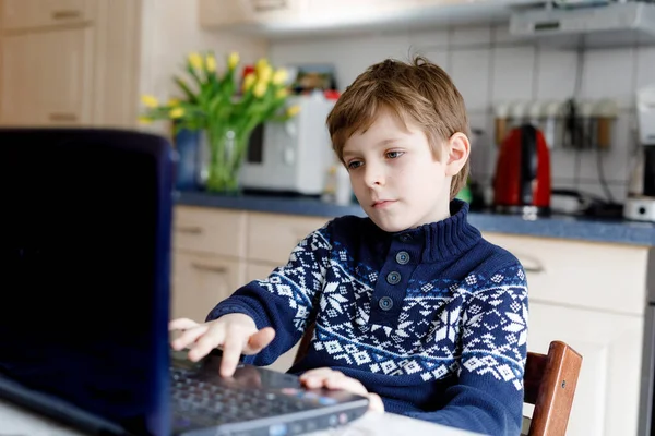 Grabben lär sig hemma på laptop för skolan. Grundskolebarn som gör läxor och använder anteckningsblock och moderna prylar. Hemskolekoncept. Att ha en videolektion med lärare. — Stockfoto