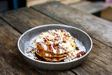 Fındıklı Amerikan krepleri, akçaağaç şurubu ve ahşap masada hindistan cevizi kreması. Kahvaltıda, kahvaltıda ya da açık kafede ya da restoranda öğle yemeğinde tatlı yiyecekler.