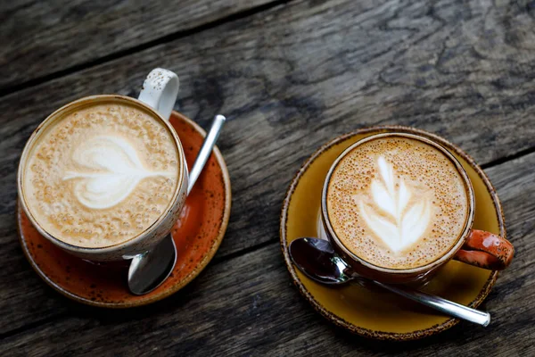 Deux tasses de café blanc plat sur une table en bois dans un café ou un restaurant en plein air. Style rustique. — Photo