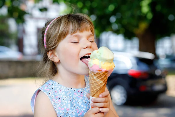 Pequena menina pré-escolar comendo sorvete em cone waffle no dia ensolarado de verão. Criança feliz come sobremesa de gelado. Comida doce em dias quentes quentes de verão. Luz brilhante, gelado colorido — Fotografia de Stock