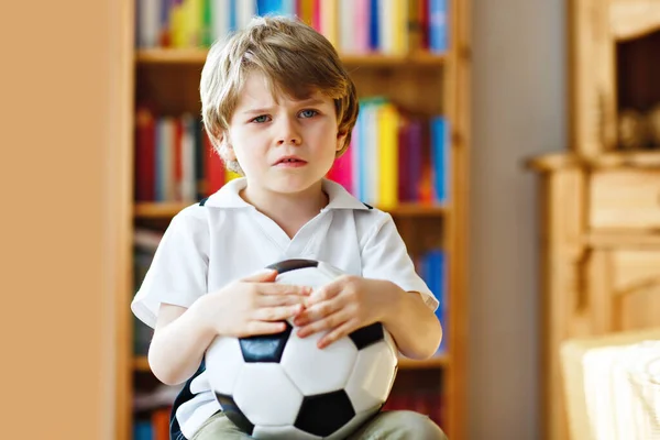 Ragazzino triste e non felice con il calcio per aver perso il calcio o la partita di calcio. bambino dopo aver guardato la partita in tv — Foto Stock