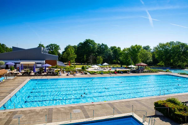 Uitzicht op openbaar open zwembad op zonnige warme zomerdag. Mensen rusten, zwemmen, verfrissen in koel schoon water, maken sport. — Stockfoto