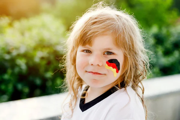 Niña rubia en edad preescolar viendo el partido de fútbol en público. Feliz alegre niño emocionado acerca de ganar el partido de partido de la selección de fútbol nacional favorita. chica con bandera alemana en la cara. —  Fotos de Stock