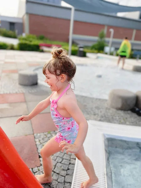 Niña preescolar salpicando en una piscina al aire libre en el cálido día de verano. Feliz niño sano disfrutando de un clima soleado en la piscina pública de la ciudad. Actividad infantil al aire libre con agua. — Foto de Stock