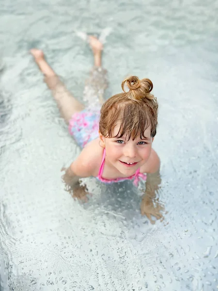 Piccola bambina in età prescolare spruzzando in una piscina all'aperto nella calda giornata estiva. Felice bambino bambino sano godendo di tempo soleggiato nella piscina pubblica della città. Attività per bambini all'aperto con acqua. — Foto Stock