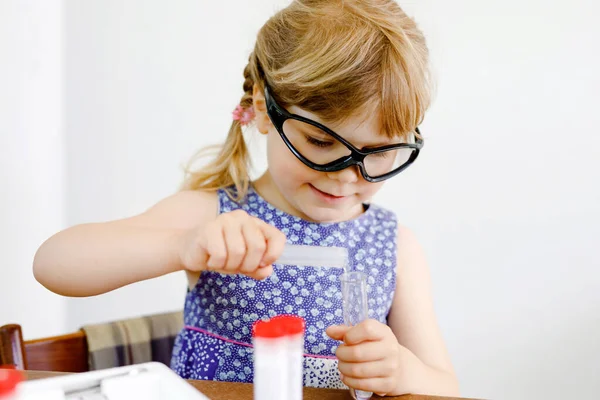 Kleines Vorschulmädchen beim chemischen Experiment im Labor in der Schule. Kleinkind mit Schutzbrille Studie Tropfen Flüssigkeit in Reagenzglas, Kaukasier, Biochemie. Chemieunterricht. — Stockfoto