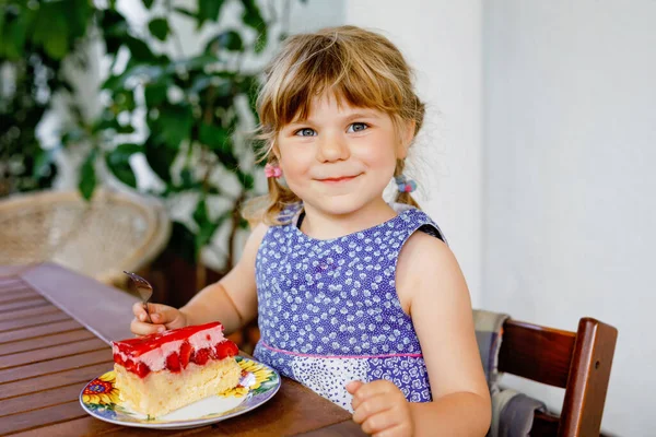 En liten förskoleflicka med jordgubbstårta. Glad barnmat tårta med färska jordgubbar. Sommardessert för familjer. — Stockfoto