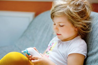 Anaokulundaki kız ateşini ölçüyor ve hasta hissediyor. Evde kızıl ötesi ısısı olan küçük bir çocuk, yüksek ateş var. Çocuk elinde dijital kızılötesi termometreyle 39 derece gösteriyor..