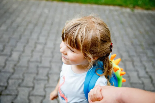 Mother accompanies preschool girl to daycare or school. Mom encourages student child to accompany her to school. Caring mother holds daughter hand as she goes to school. Happy positive girl.