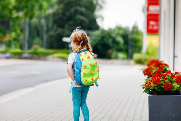 可爱的学龄前小女孩要去上幼儿园。健康的幼儿步行到托儿所和幼儿园。快乐的孩子背着背包在城市街道上，户外。城市，交通，学校路上的安全. — 图库照片