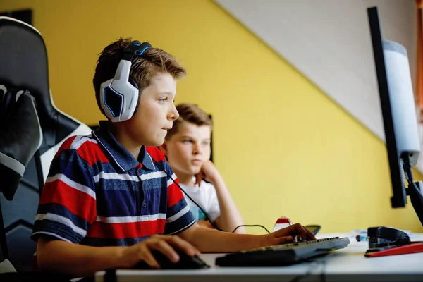 Två barn pojkar spelar dataspel på skrivbordet dator. Modern missbrukaraktivitet för barn. Syskon och vänner spelande hemma. — Stockfoto