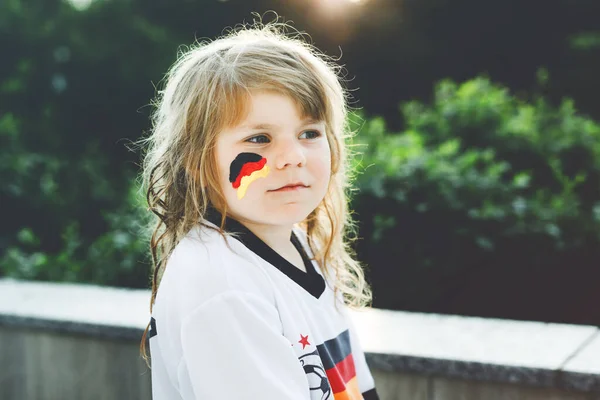 Piccola ragazza bionda in età prescolare guardando la partita di calcio coppa di calcio sulla visualizzazione pubblica. Felice gioioso bambino eccitato per vincere partita della squadra di calcio nazionale preferita. ragazza con bandiera tedesca sul viso. — Foto Stock