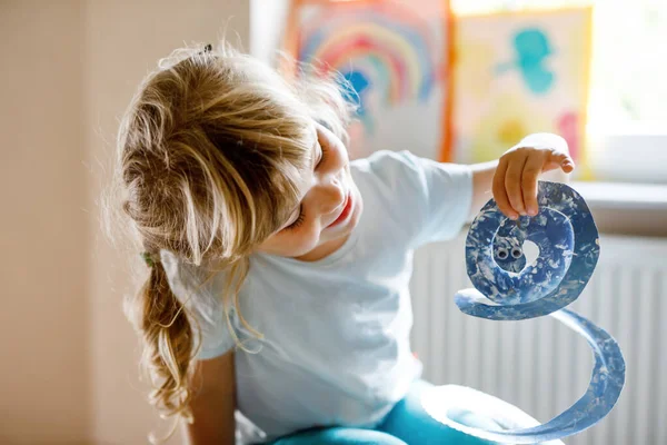 Mała dziewczynka przedszkola malowanie z kolorami palców co węża zwierząt rzemiosła w domu lub żłobka. Aktywność w pomieszczeniach z szczęśliwym dzieckiem kreatywnym, nauka w domu z rodzicami — Zdjęcie stockowe
