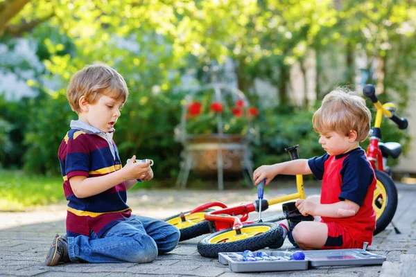İki mutlu çocuk bisiklet zincirini tamir ediyor ve denge tekerleğini değiştiriyor. — Stok fotoğraf