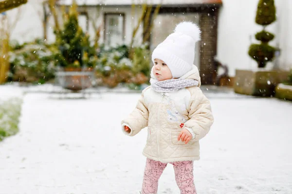 Gelukkig klein meisje maken eerste stappen buiten in de winter door de sneeuw. Leuke peuter die leert lopen. Kind heeft plezier op koude besneeuwde dag. Babys eerste sneeuw, activiteit. Winterwandeling buiten — Stockfoto