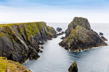 Malin Head, Donegal, İrlanda 'da engebeli bir manzara. Kayalıkları olan dalgalı bir sahil, sisli bulutlu bir günde koyunlu yeşil kayalık bir arazi..