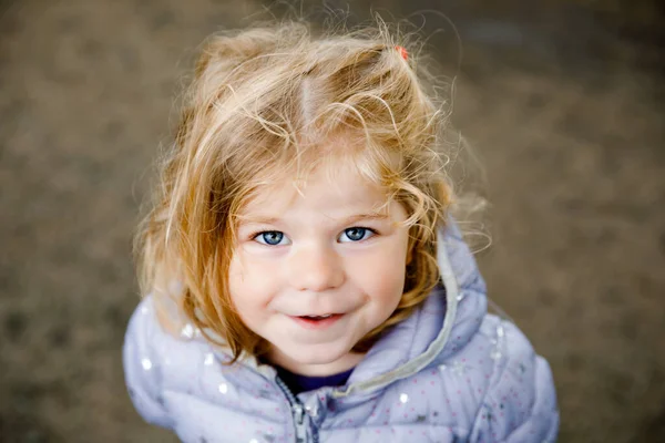 Retrato de la niña sonriente feliz al aire libre. Niña con el pelo rubio mirando y sonriendo a la cámara. Feliz niño sano disfrutar de la actividad al aire libre y jugar. — Foto de Stock