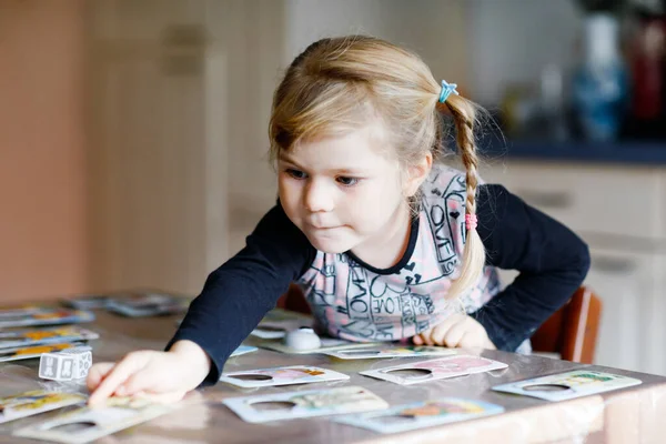 Adorable linda niña jugando juego de cartas imagen. Feliz niño sano entrenando la memoria, pensando. Creativo en interiores ocio y educación de los niños durante la pandemia coronavirus covid enfermedad de cuarentena — Foto de Stock