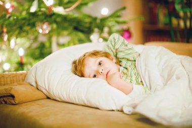 Noel ağacının altında uyuyan ve Noel Baba 'yı evde, evde hayal eden tatlı sarışın çocuk. Geleneksel Hıristiyan festivali. Mutlu çocuk Noel 'de hediye bekliyor. Samimi yumuşak ışık