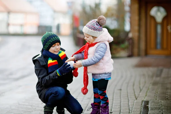 Peuter meisje en schooljongen in kleurrijke winter mode kleding hebben plezier en spelen met sneeuw, buiten tijdens de sneeuwval. Actief buitenrecreatie met kinderen. Gelukkige broers en zussen, familie — Stockfoto