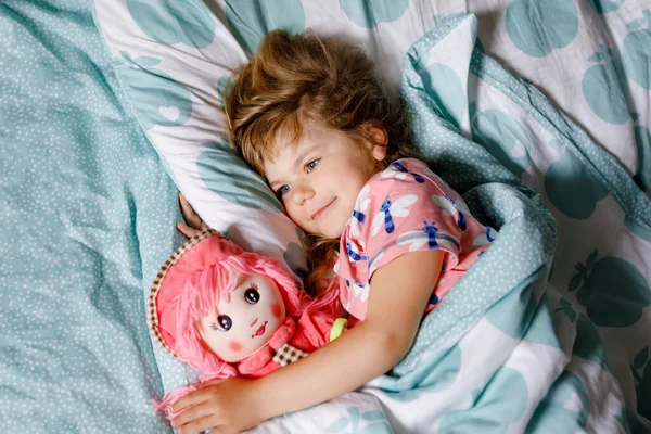 Мила маленька дівчинка, яка спить у ліжку з улюбленою м'якою плюшевою іграшковою лялькою. Чарівна дитина, яка мріє, здоровий сон дітей вдень. Глибокий сон малюка. Діти відпочивають . — стокове фото