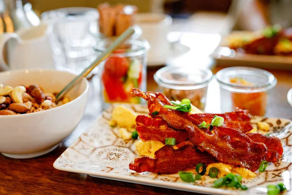 Bord till frukost utomhus på sommaren med olika sylter, bröd, kaffe, croissanter, ägg, bacon müsli och apelsinjuice — Stockfoto