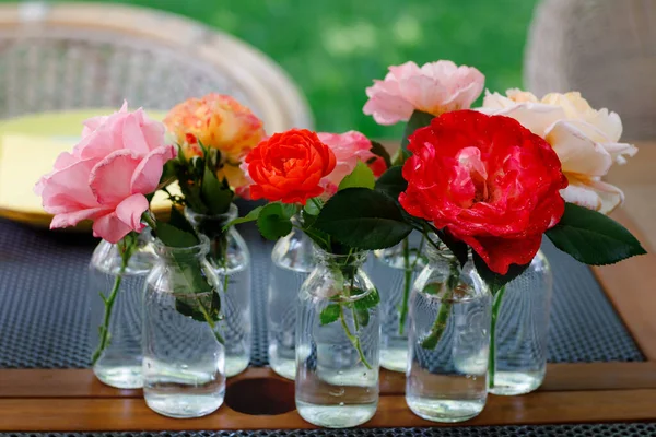 Variation or group of garden roses flowers in small vases or bottles. Colorful flower arrangement or decoration in rainbow colors. Home or garden, terrace decor concept. — Stock Photo, Image