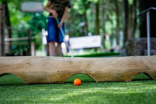 Шкільний хлопчик грає в міні-гольф з сім'єю. Щаслива дитина отримує задоволення від активного відпочинку. Літній спорт для дітей та дорослих, на відкритому повітрі. Сімейний відпочинок або курорт . — стокове фото